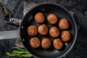 fried-vegan-plant-based-meatballs-skillet-with-herbs-black-background-top-view