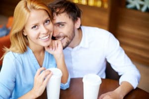 Portrait of young couple sitting by table in cafe