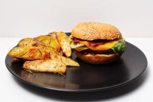 vegan-food-closeup-homemade-cheeseburger-baked-potatoes-black-plate