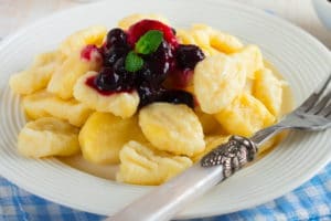 cheese-dumplings-gnocchi-with-sauce-black-currants-white-ceramic-plate-healthy-breakfast-selective-focus