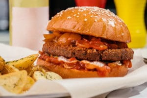 meatless-burger-with-vegetable-patty-iceberg-lettuce-caramelized-onion-salsa-sauce-vegan-burger-table-cafe-with-lemonade-sauces-potatoes-mockup