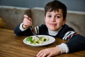 handsome-european-school-age-boy-eating-healthy-vegan-meal