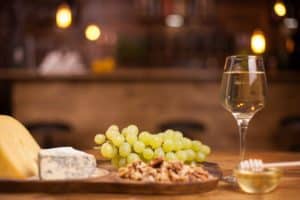 photo-fresh-grapes-wineglass-wooden-table-french-cheese-degustation-tasty-walnuts_482257-19784