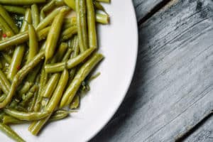 High angle shot of boiled green beans in a white plate - perfect for an article about vegan food